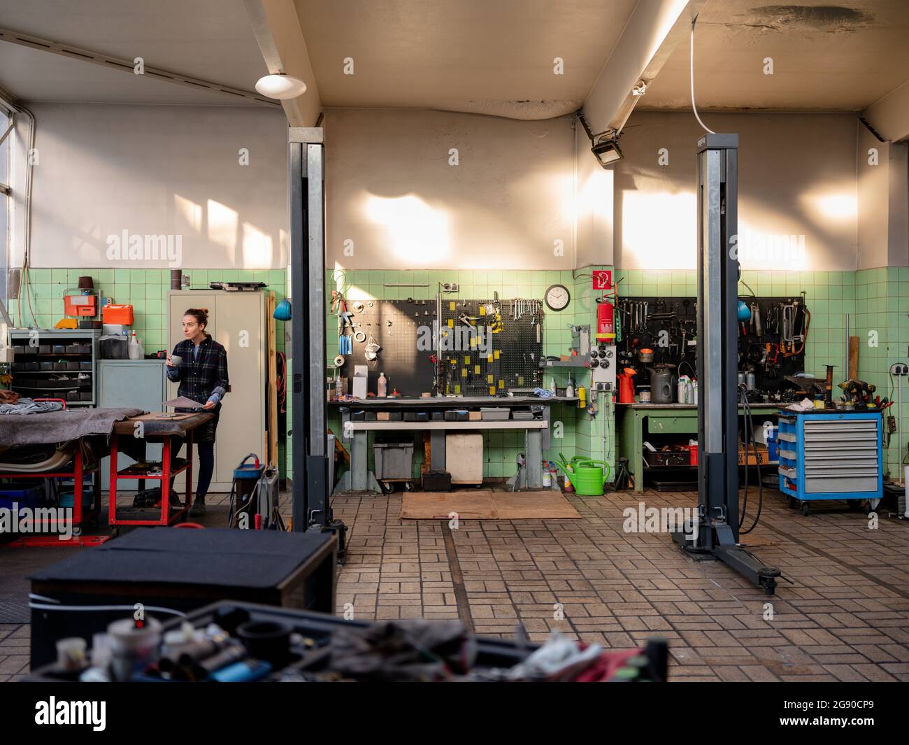 Meccanico femminile con lavoro documentale in officina di riparazione auto Foto Stock