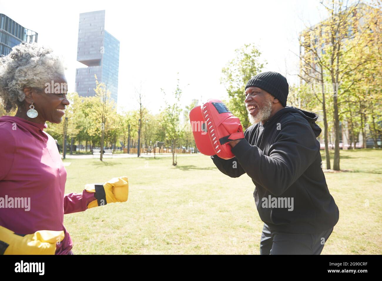 Donna sorridente che pratica pugilato con l'uomo al parco Foto Stock