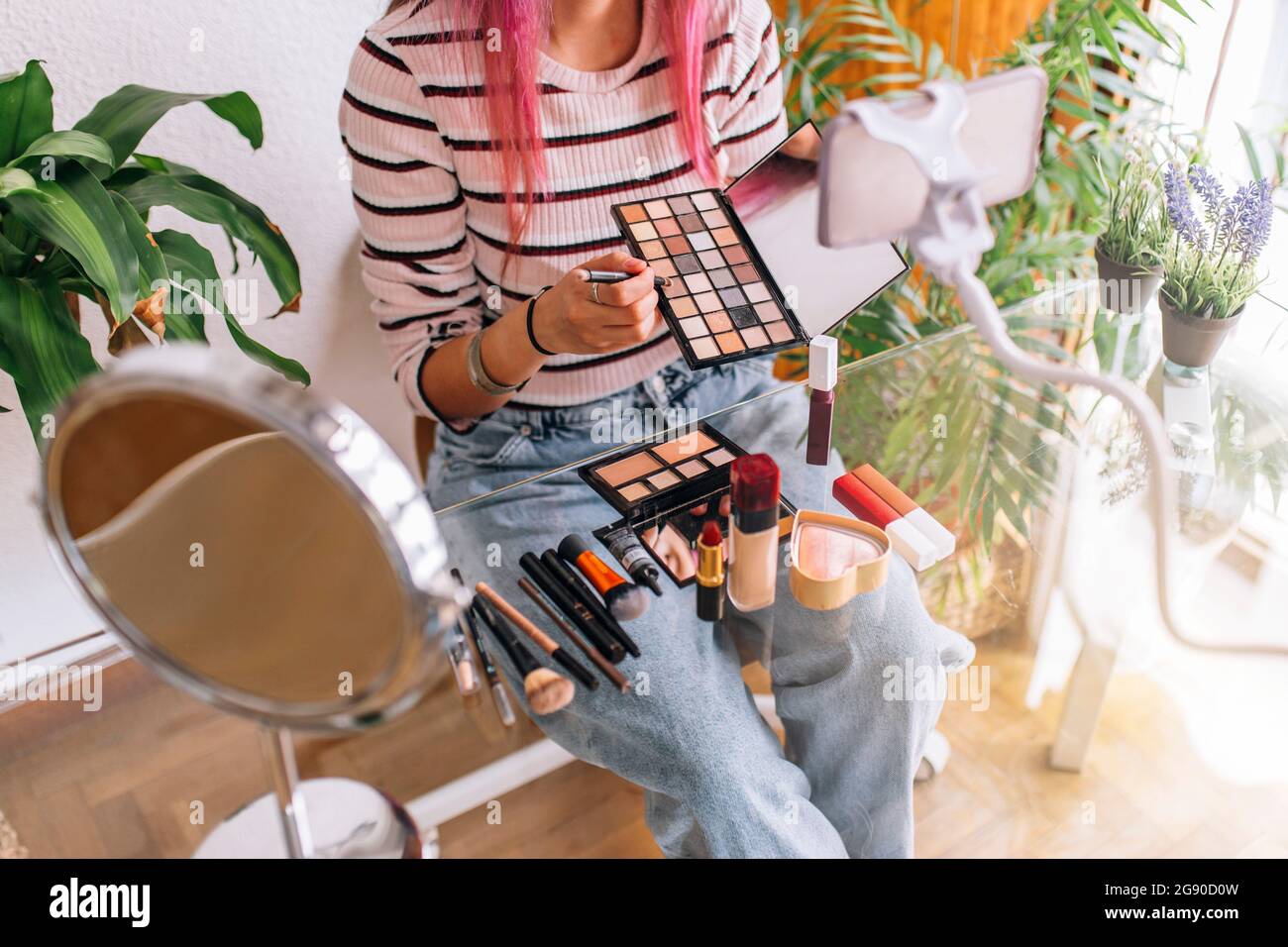 Vlogger femmina che fa make-up tutorial attraverso il telefono cellulare a casa Foto Stock