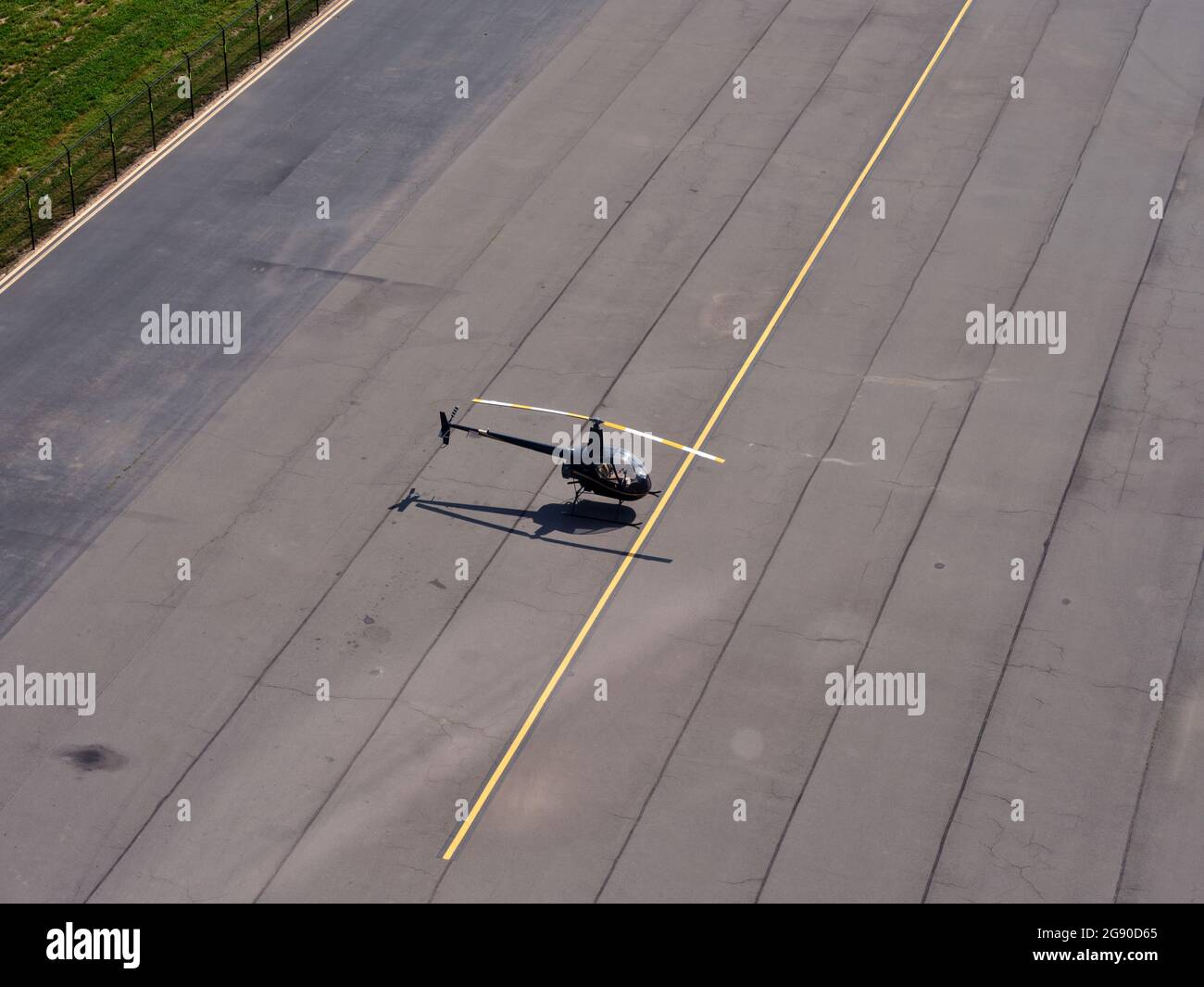 Vista aerea dell'elicottero Robinson R22 in piedi in mezzo alla pista vuota dell'aeroporto Foto Stock