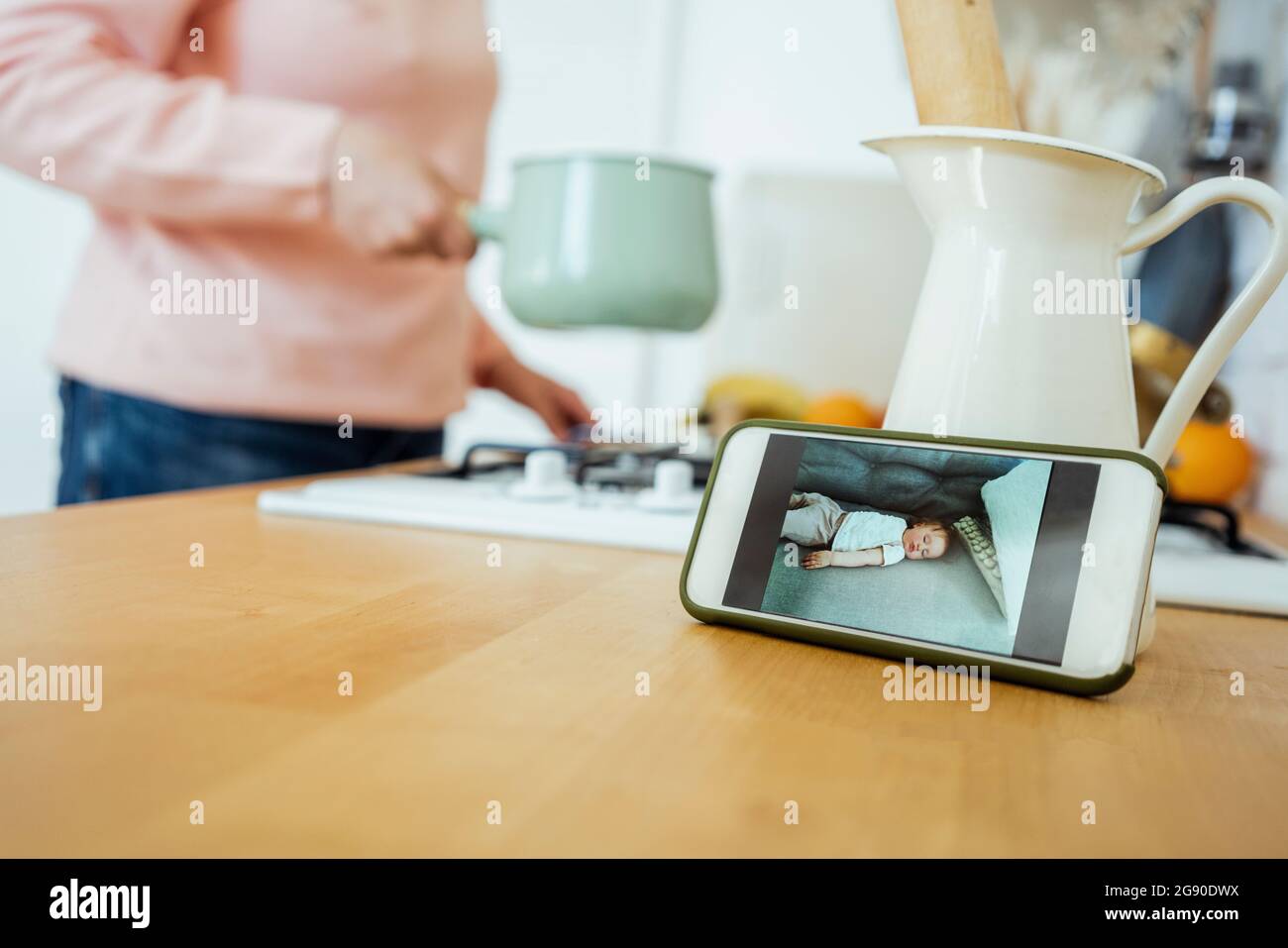 Donna che prepara il cibo durante la videochiamata attraverso il telefono cellulare in cucina Foto Stock