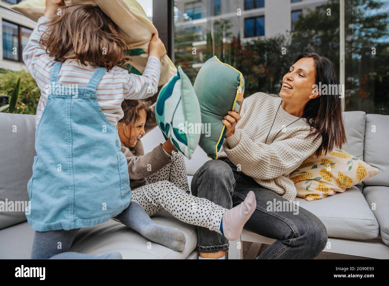 Madre e le figlie che fanno il cuscino che combattono al cortile Foto Stock