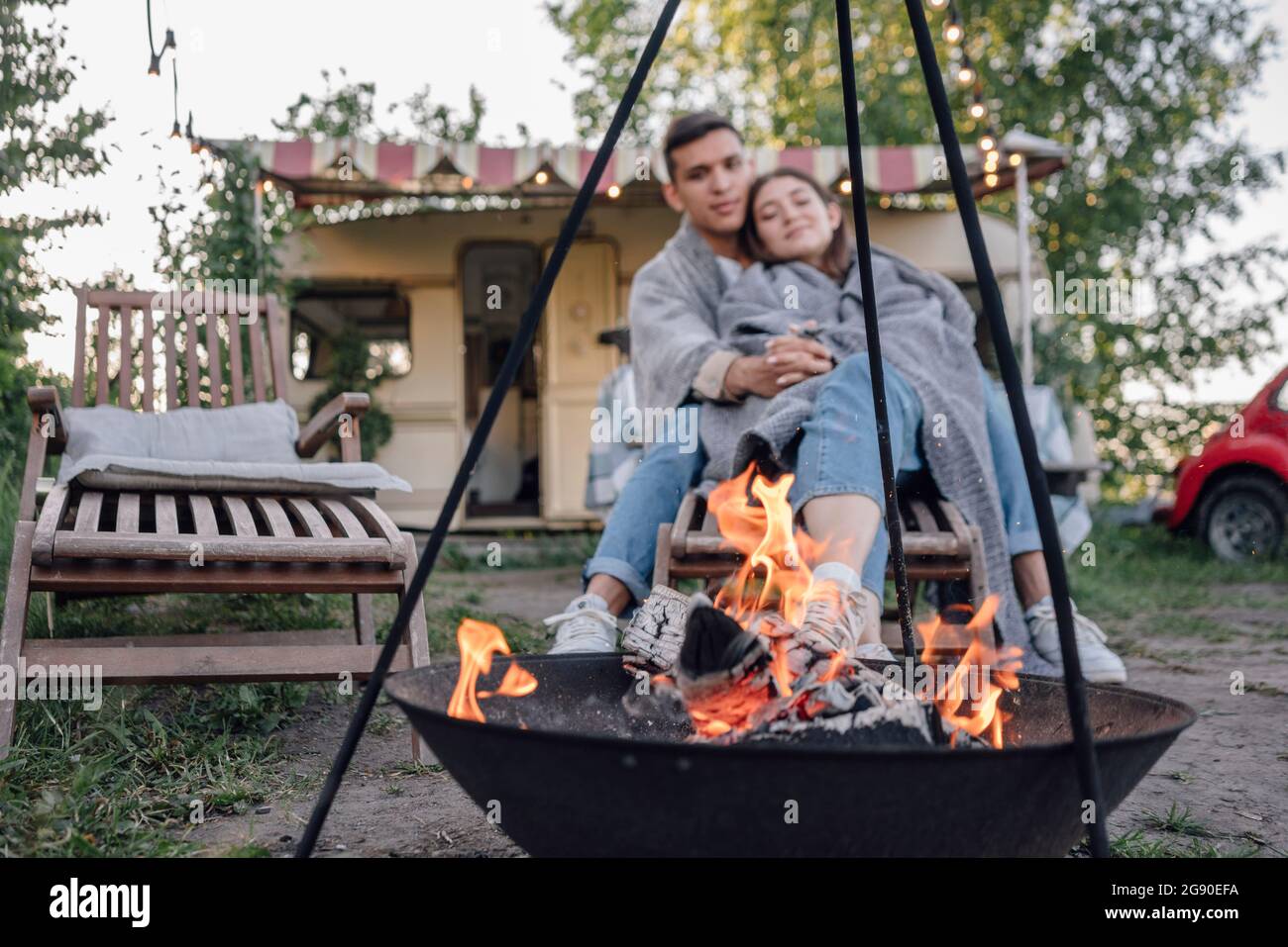 Giovane coppia avvolta insieme in coperta vicino a buca del fuoco Foto Stock