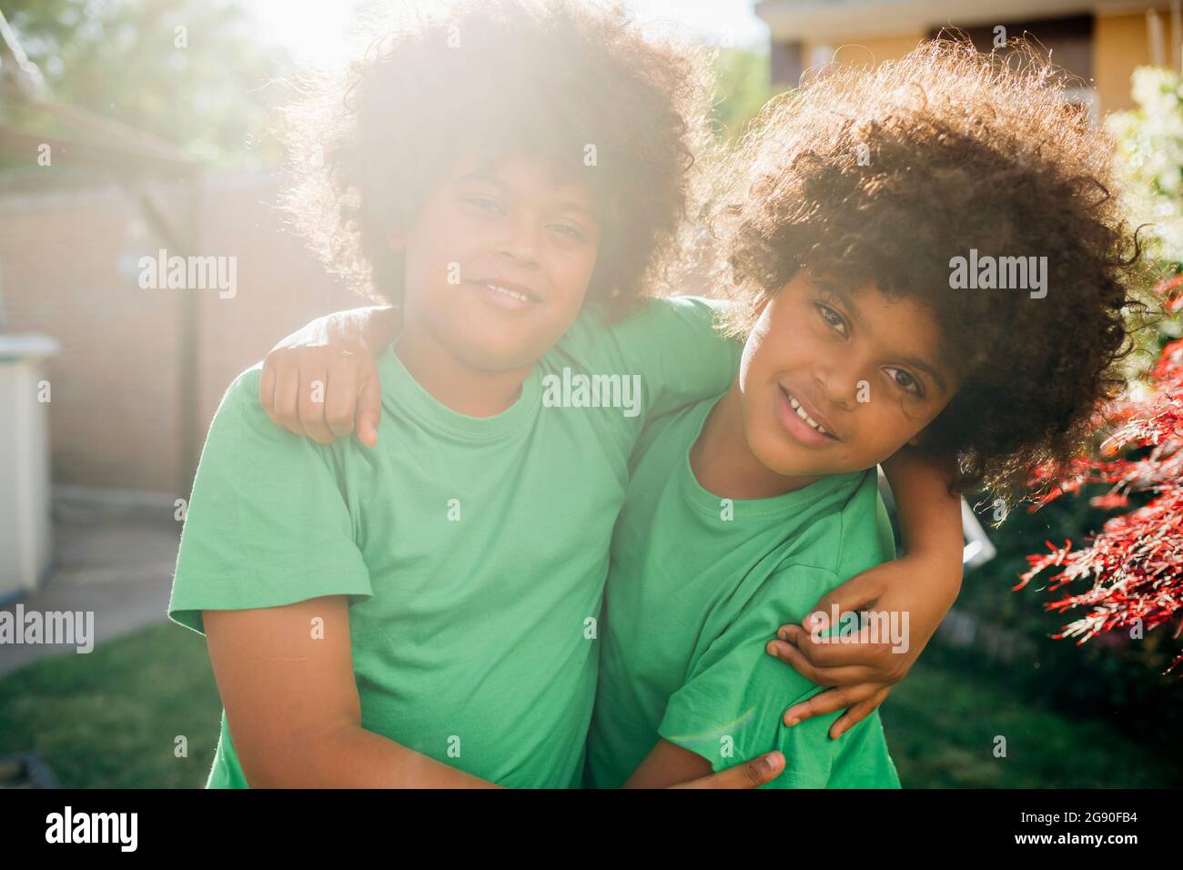 Fratelli gemelli con braccio intorno nel cortile posteriore Foto Stock