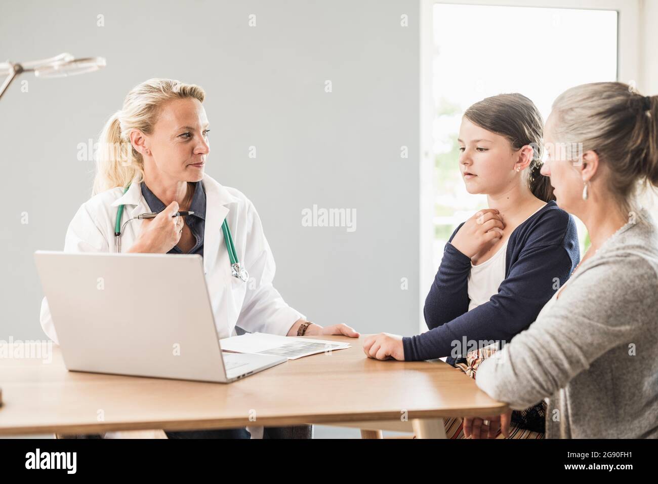 Medico con notebook che guarda paziente e donna in ufficio Foto Stock