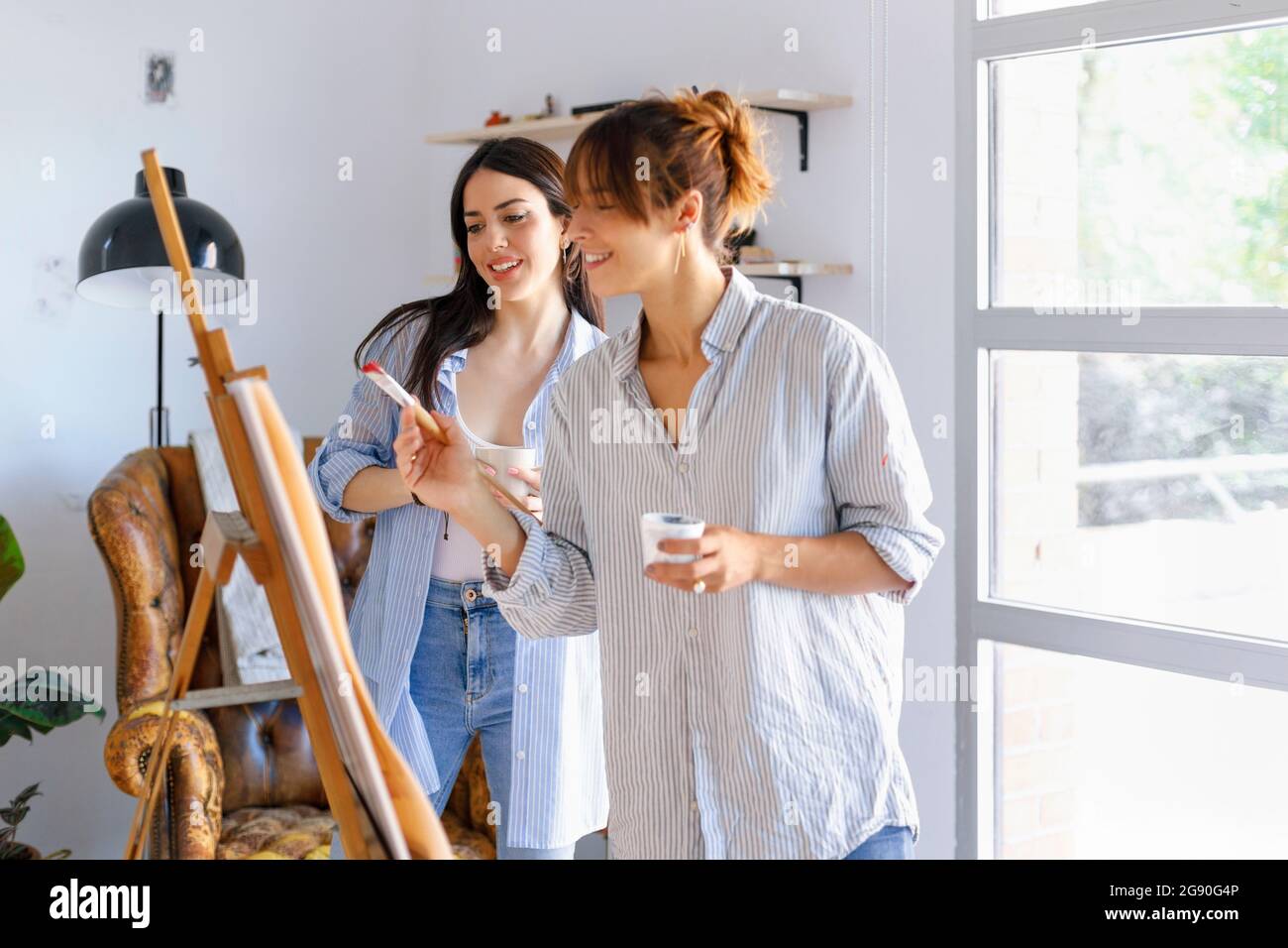 Sorridenti professionisti creativi femminili che parlano di pittura in studio d'arte Foto Stock