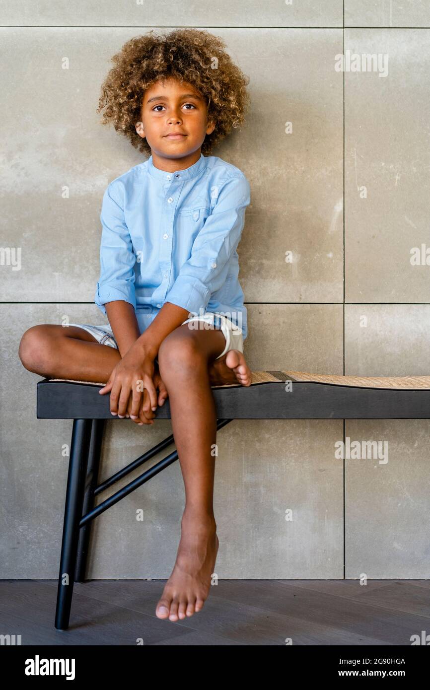 Ragazzo innocente seduto sul banco a casa Foto Stock