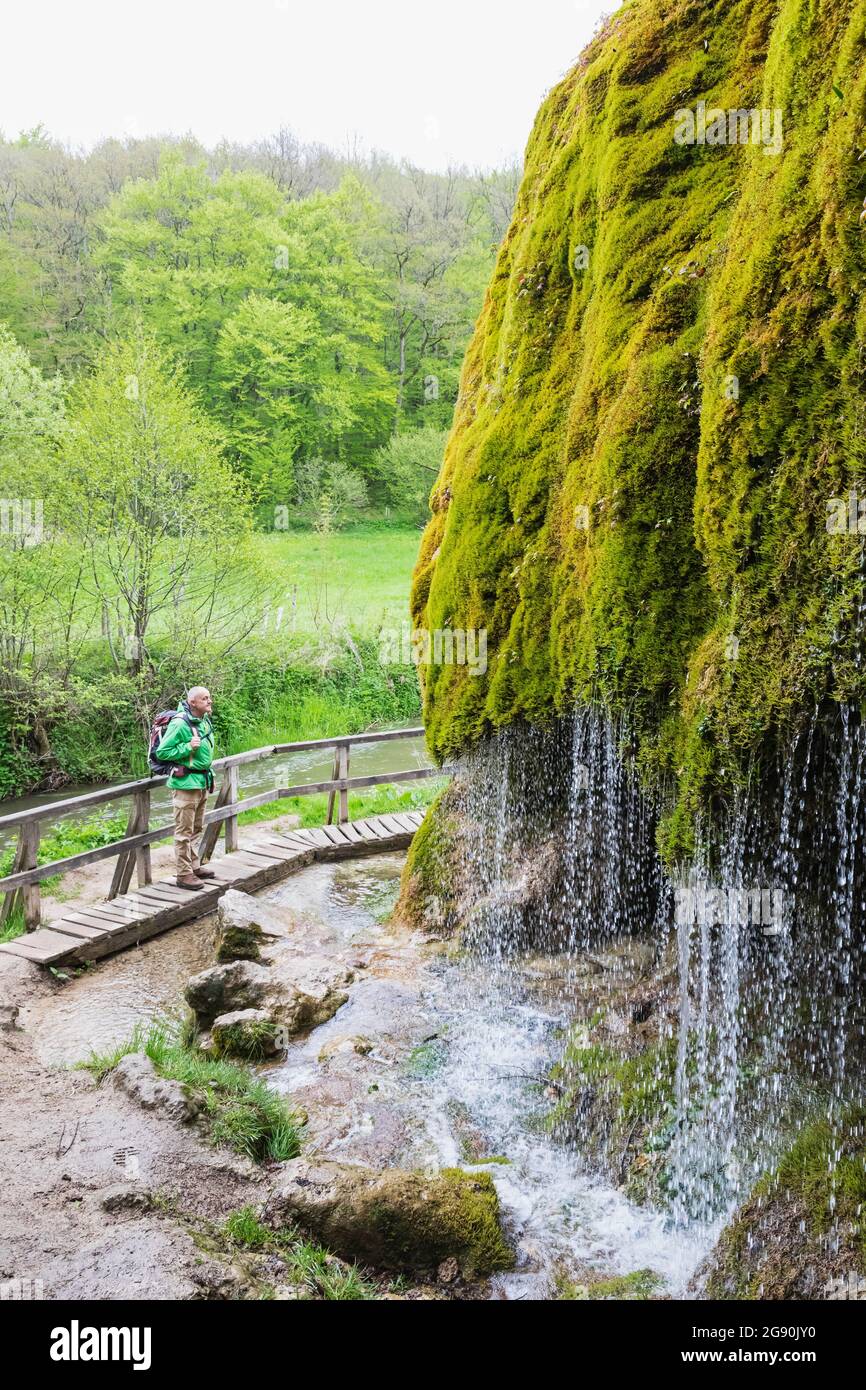 Escursionista senior ammirando la cascata Dreimuhlen che cade giù pendio di Mossy Foto Stock