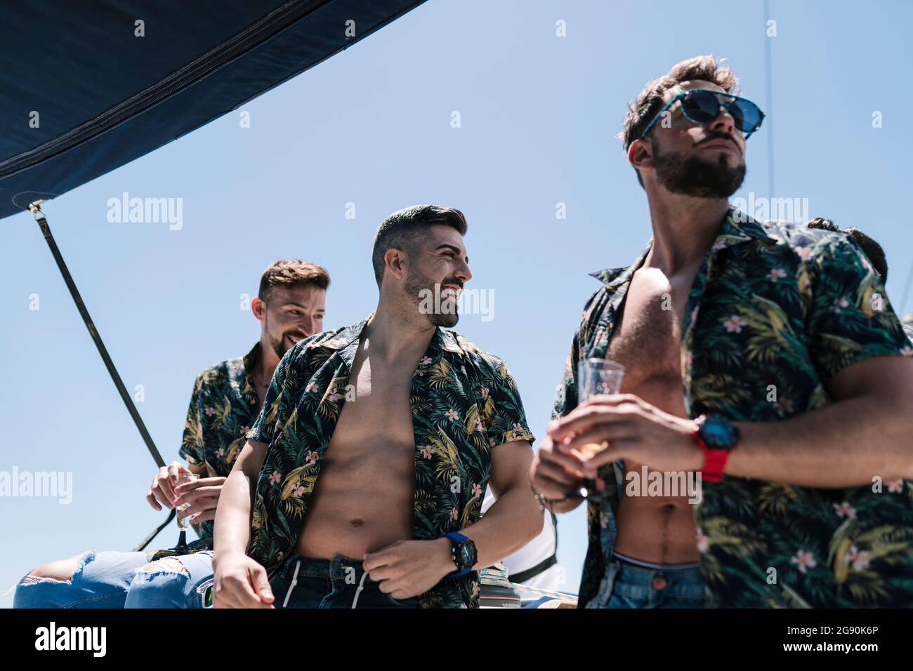 Gli uomini bearded che guardano via mentre viaggiano in yacht durante l'estate Foto Stock