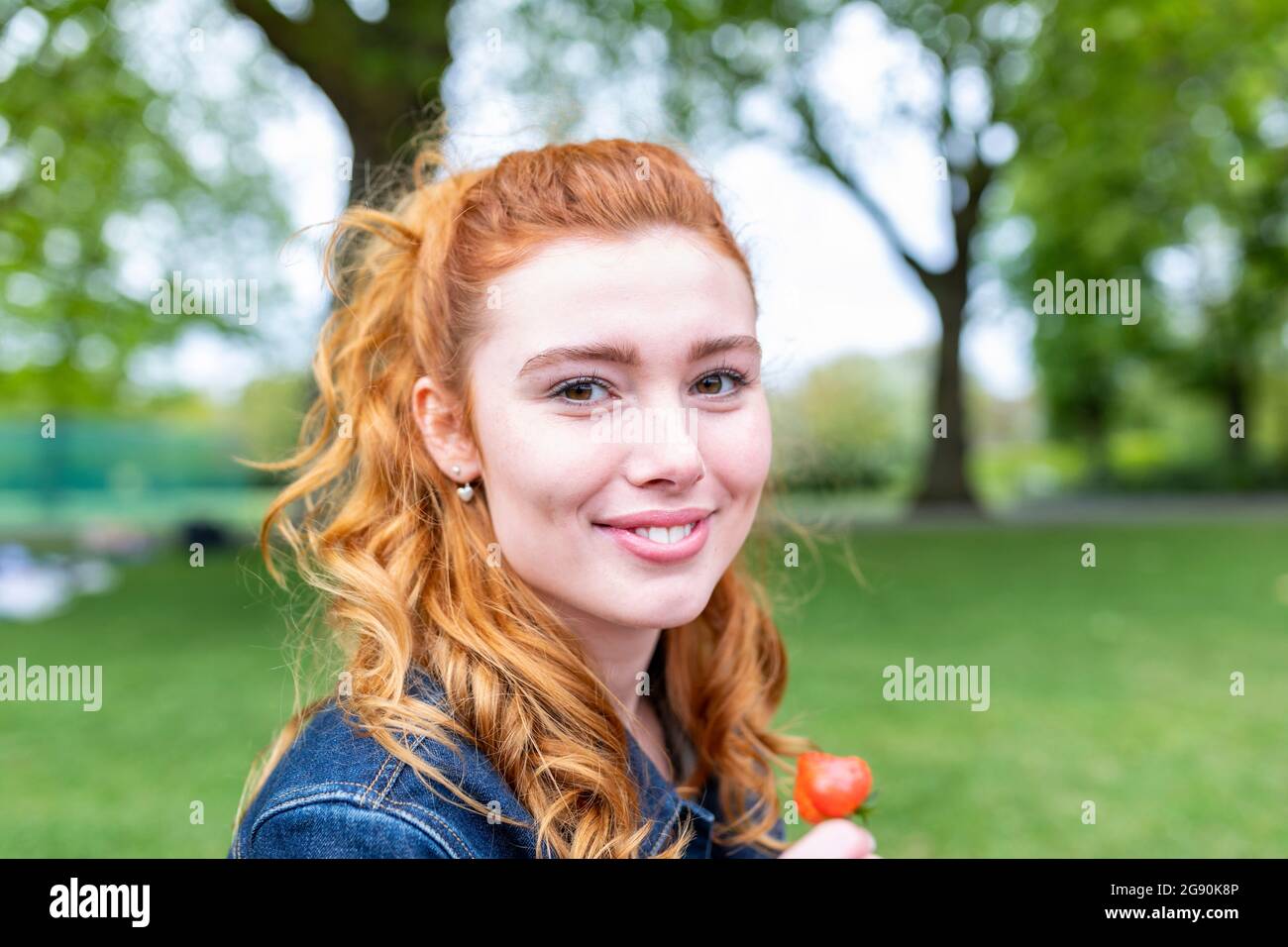 Donna rossa sorridente al parco Foto Stock