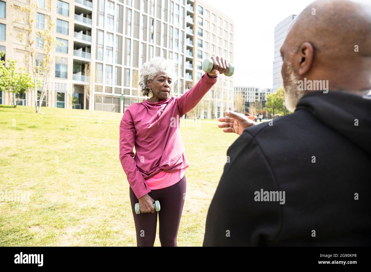 Donna anziana che si esercita con manubri nel parco pubblico Foto Stock