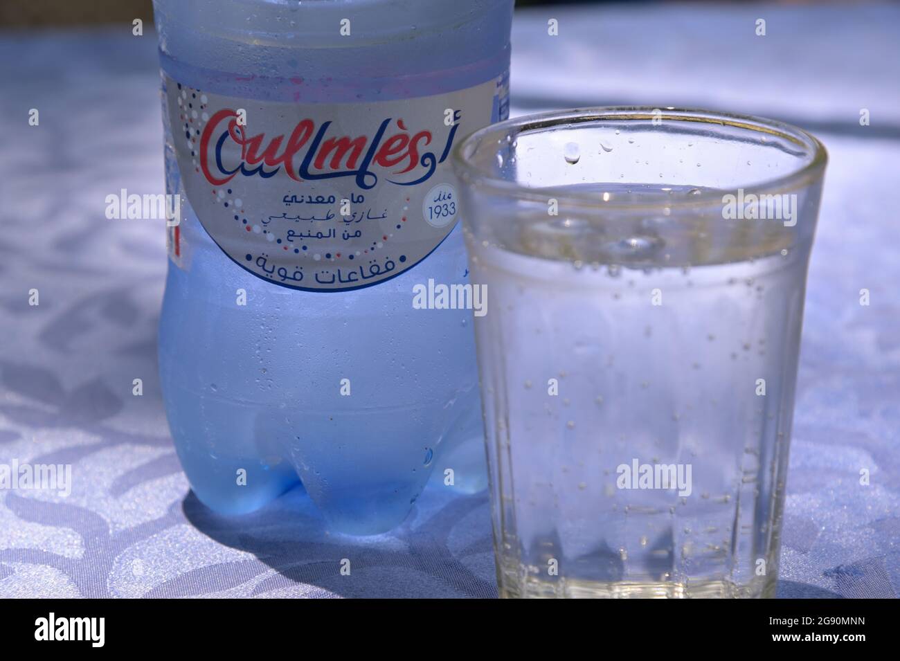 Una bottiglia e un bicchiere di popolare acqua minerale Oulmes, High Atlas ma Foto Stock