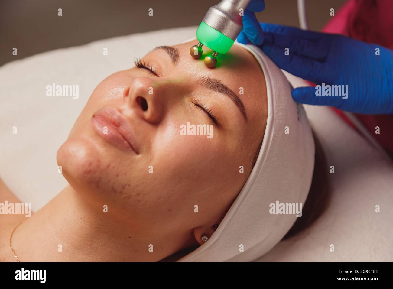 Donna giovane con acne che ottiene pulizia della pelle di ultrasuono e trattamento del viso al salone di bellezza Foto Stock