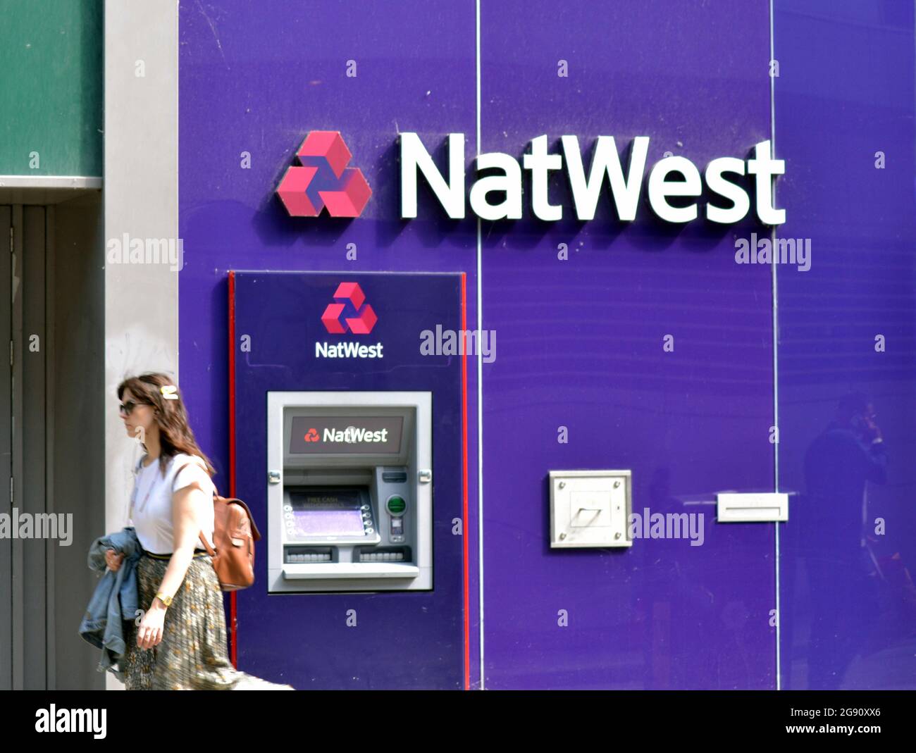 Una donna passa accanto a una filiale della banca Natwest e atm nel centro di Manchester, Inghilterra, regno unito Foto Stock