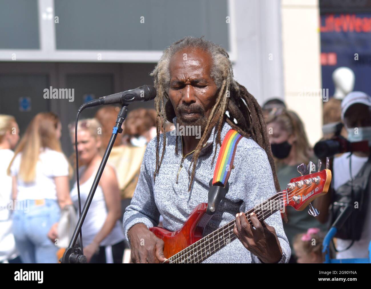 Un cantante nero maschile con una chitarra busking nel centro di Manchester, Inghilterra, regno unito Foto Stock