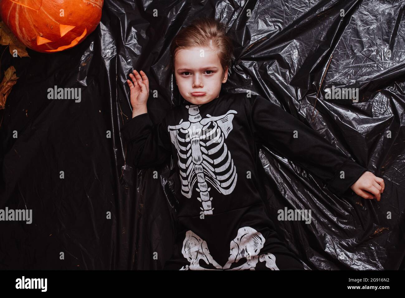 Happy Halloween, bambino che indossa in un costume scheletro facendo sorridere su sfondo grigio Foto Stock