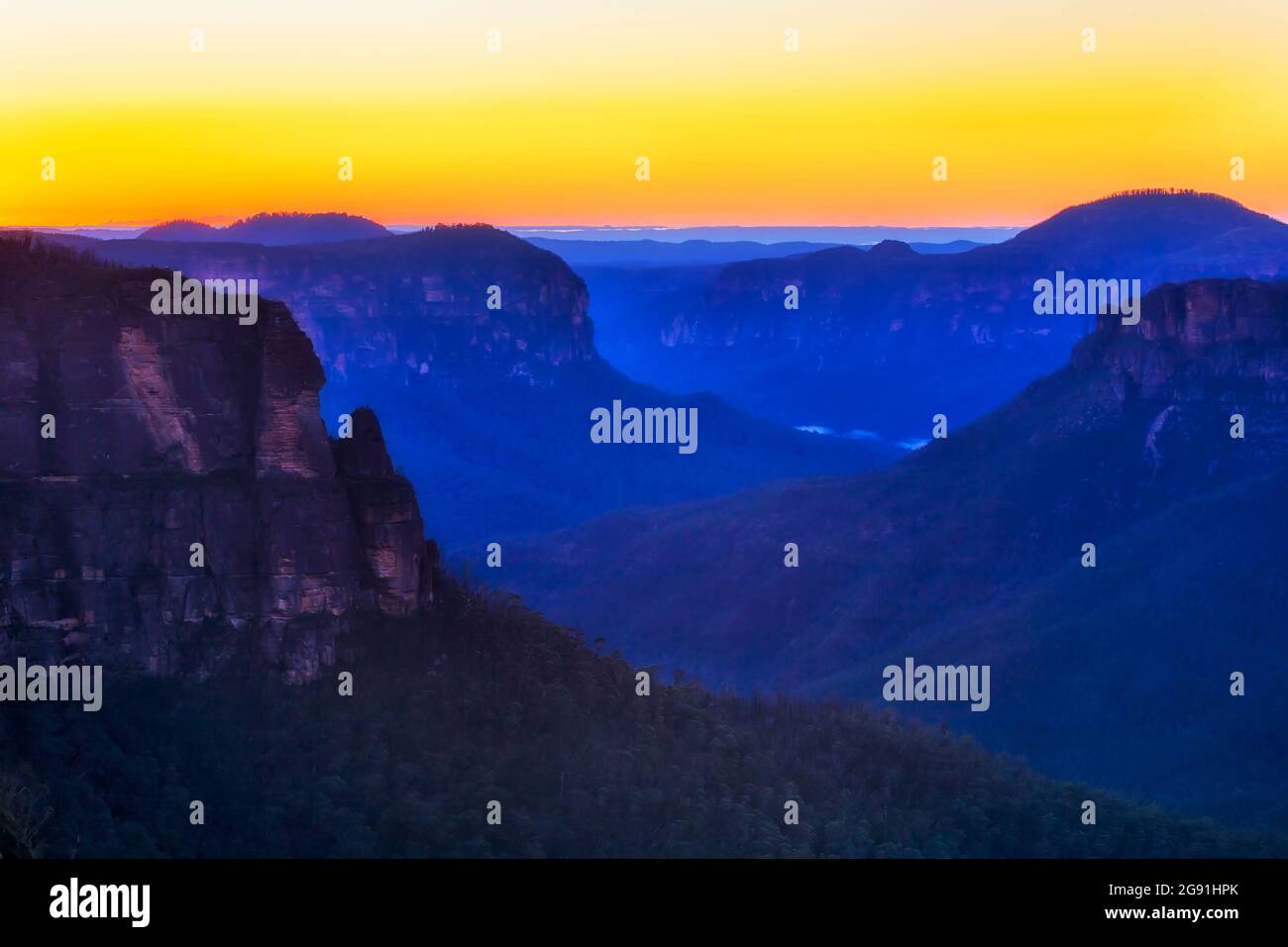 Ampio e lungo canyon nelle Blue Mountains dell'Australia con la scogliera di roccia Pulpit al largo di Govetss salto al sorgere del sole. Foto Stock