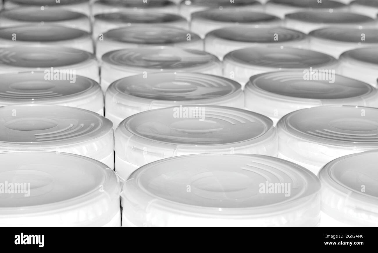Contenitori in plastica bianca con coperchi allineati in file con ombre e texture, vista ad angolo basso. Foto Stock