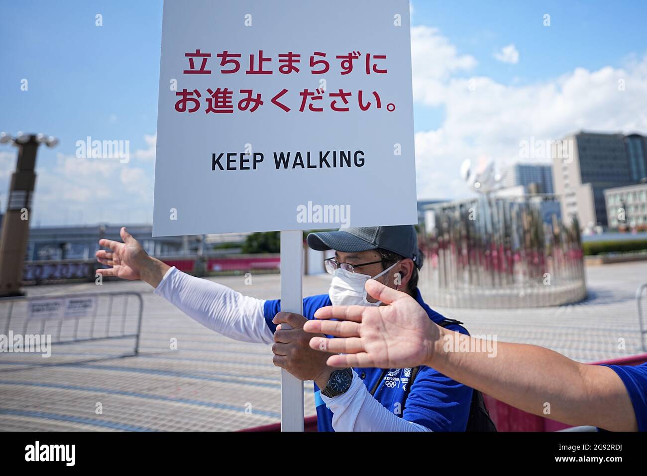 Tokio, Giappone. 24 luglio 2021. Un dipendente tiene in mano un cartello che dice "continua a camminare" e gesti con un collega per continuare a camminare. Le Olimpiadi di Tokyo 2020 si terranno dal 23.07.2021 al 08.08.2021. Credit: Michael Kappeler/dpa/Alamy Live News Foto Stock