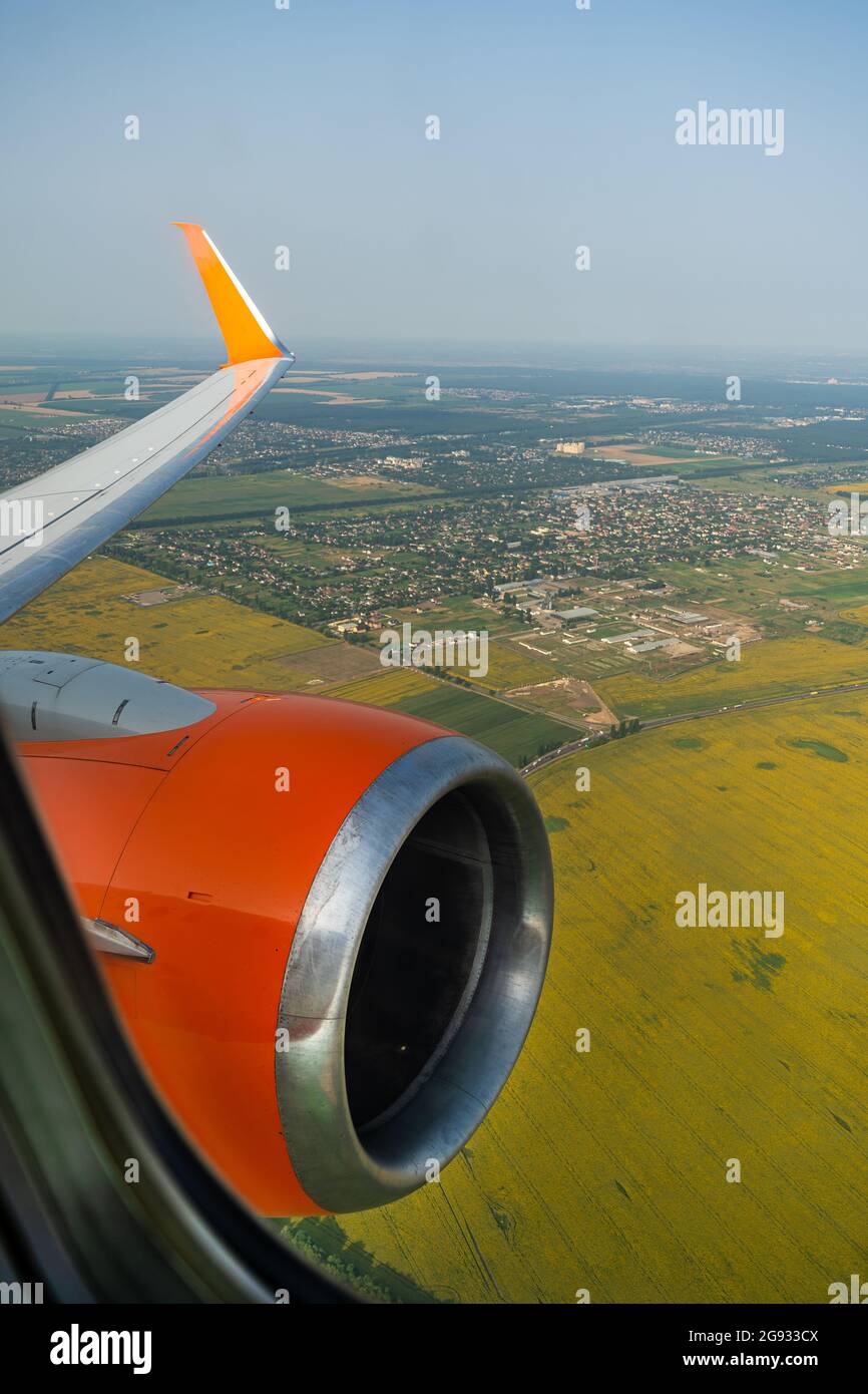 Motore aereo in volo. Vista terrestre attraverso la finestra dell'aeroplano. Campi, strade, fiumi da una vista a volo d'uccello. Oblò. Guarda fuori la finestra di un aereo volante. Vista dall'alto del terreno. Foto Stock