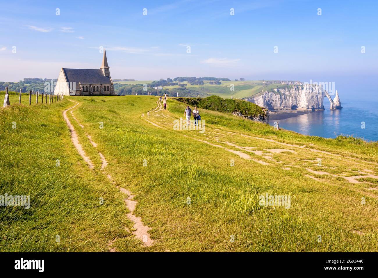 I turisti passeggiano lungo il percorso costiero sulla scogliera Amont a Etretat, in Normandia, passando per la cappella di Notre-Dame de la Garde con l'arco e l'ago. Foto Stock