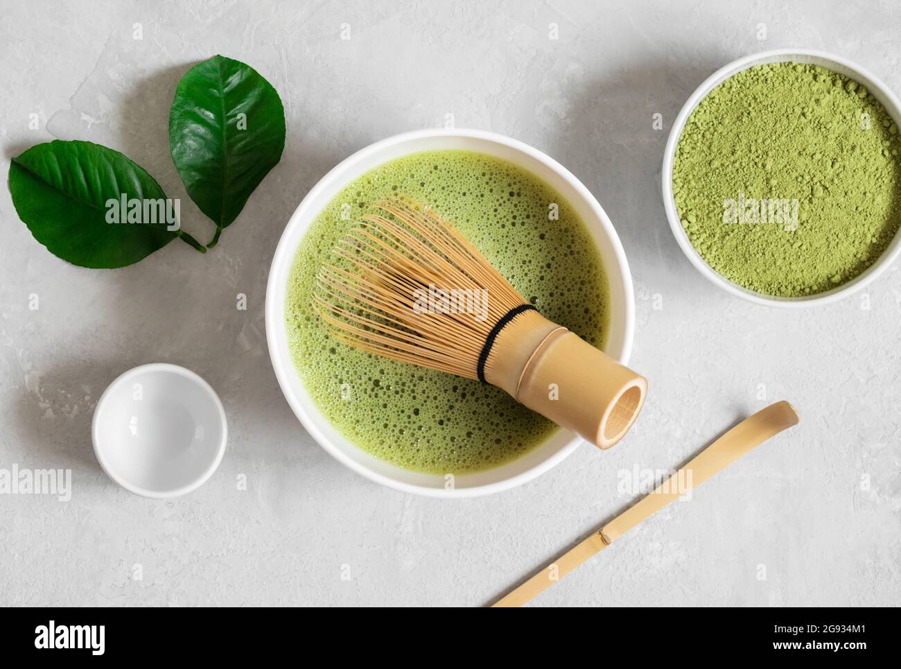 Cucinando il tè matcha con un tradizionale chioseup di bambu'. Tè verde Matcha su sfondo grigio. Bevanda tradizionale giapponese. Vista dall'alto. Foto Stock