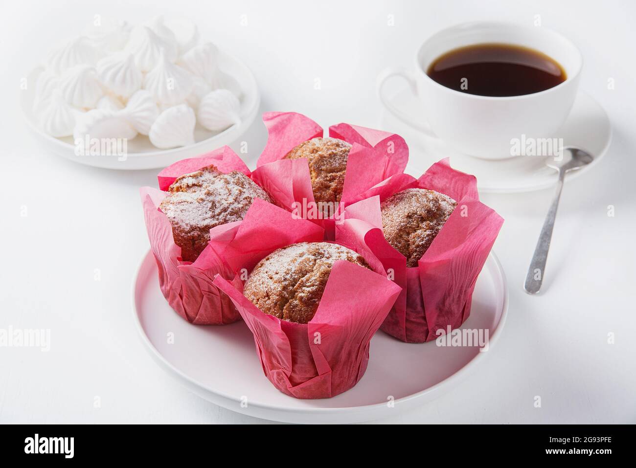 Muffin, marshmallows e caffè nero su un tavolo bianco. Foto Stock