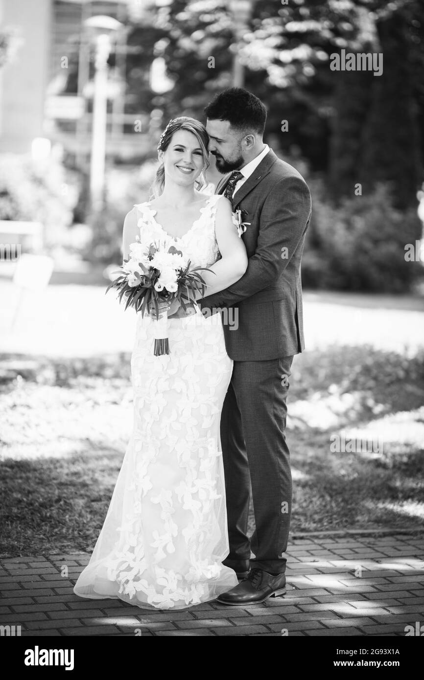 Ritratto a corpo pieno in scala di grigi di una coppia allegra di nozze in posa nel parco Foto Stock
