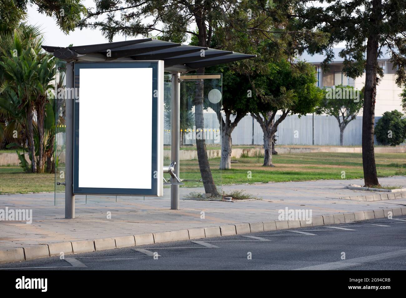 Cartellone bianco verticale sulla strada della città con alberi verdi Foto Stock