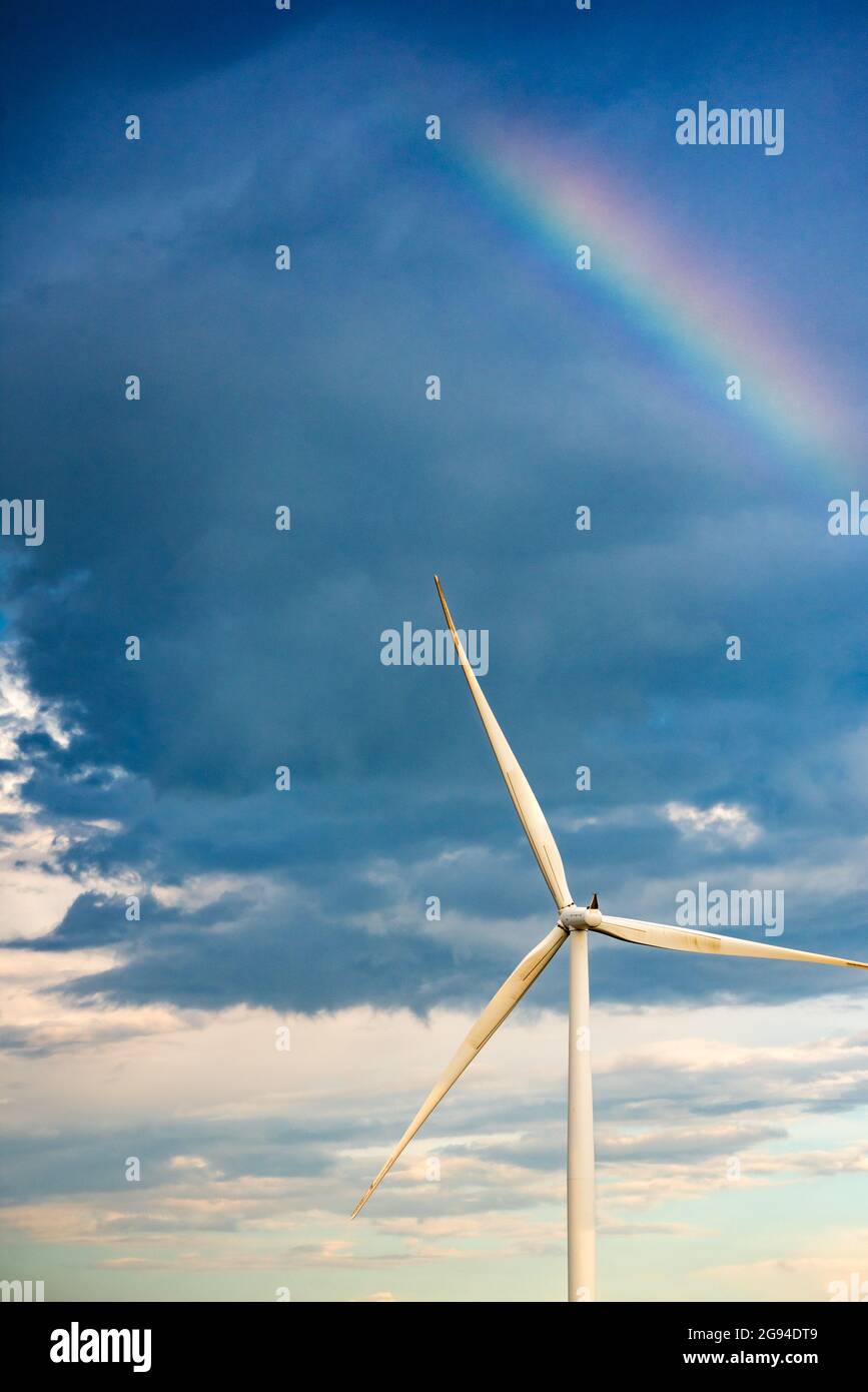 arcobaleno in un cielo scuro sopra una turbina eolica Foto Stock