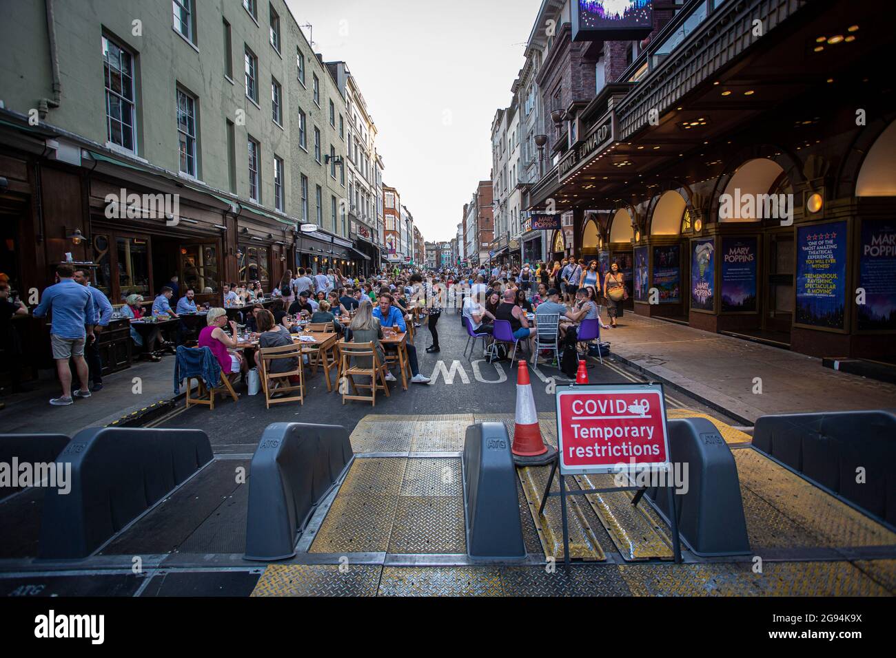 La gente in un ristorante è vista dietro un segno 'di restrizioni temporanee del covid' nel Soho di Londra che solleva tutte le restrizioni sulla vita quotidiana in Inghilterra. Foto Stock