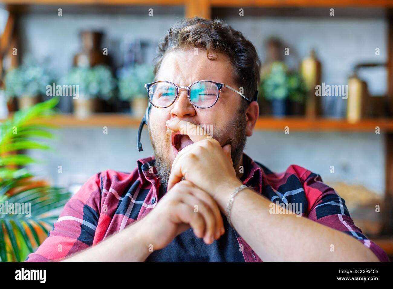 Un giovane di fronte a una webcam durante una videochiamata online. Urla e gli copre la bocca con la mano. Il concetto di burnout dallo stesso tipo o Foto Stock