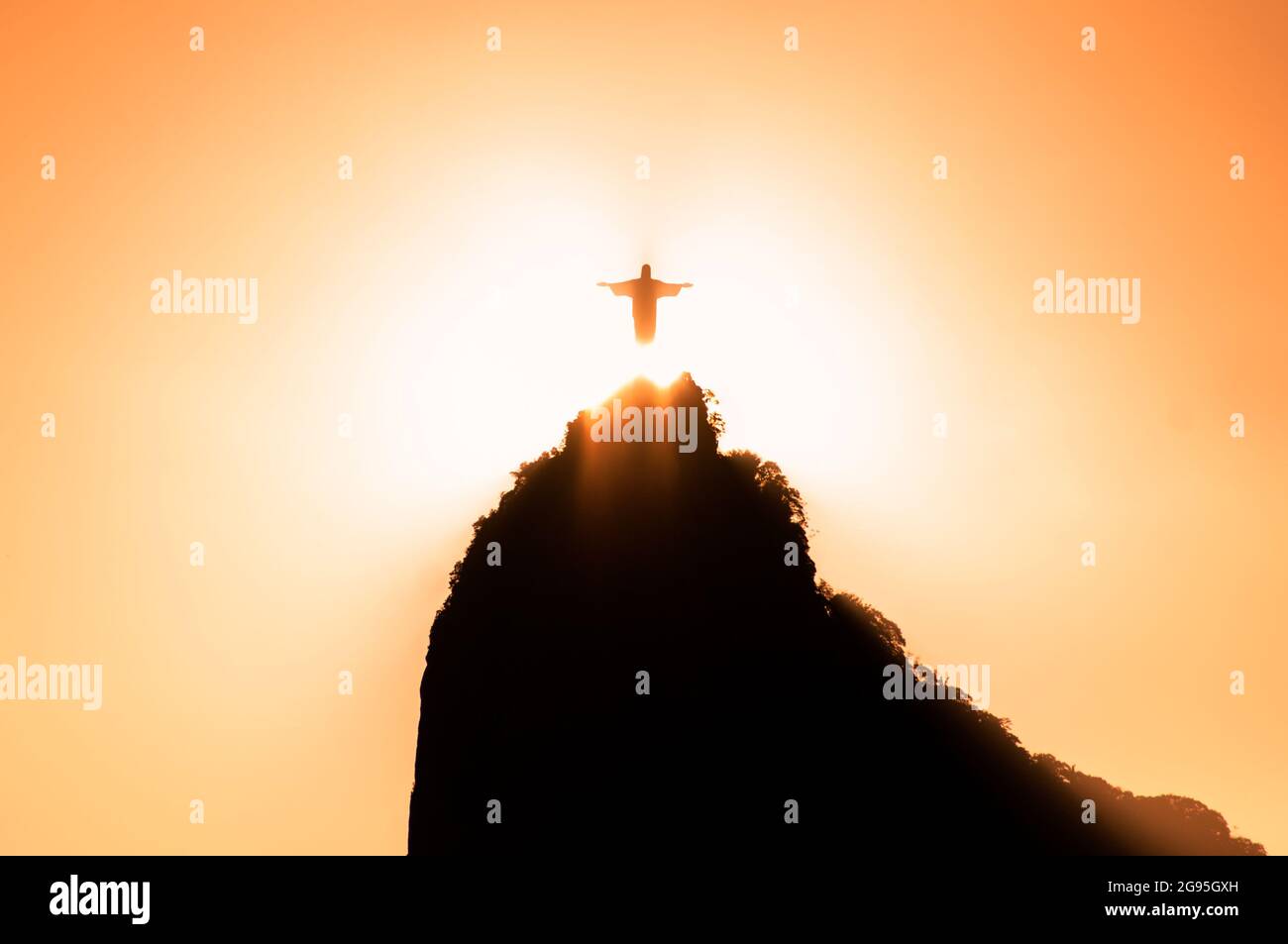 Il sole scende proprio dietro la statua del Cristo Redentore sul monte Corcovado a Rio de Janeiro Foto Stock