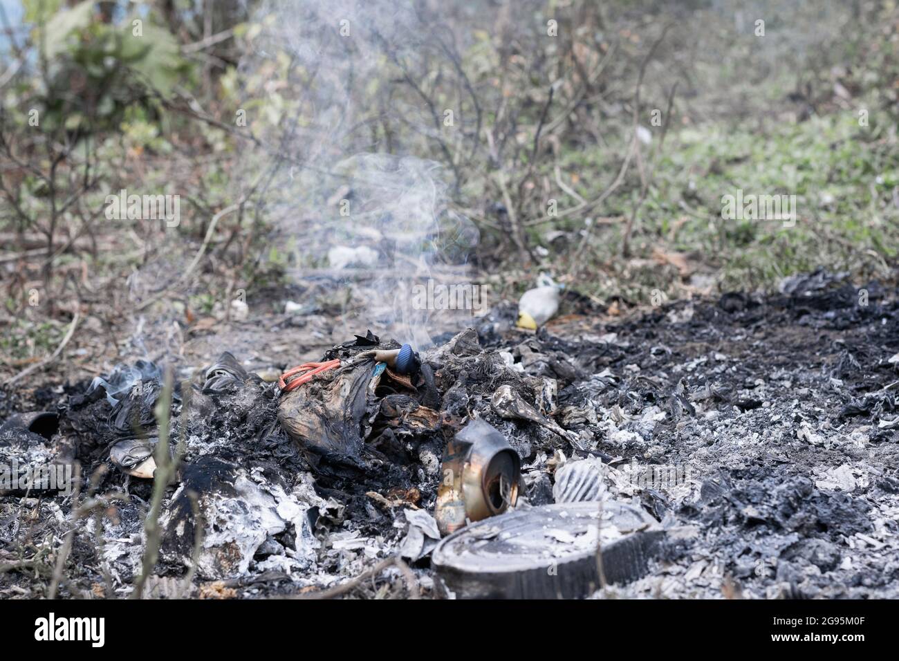 Inquinamento ambientale (polución), miscela di rifiuti domestici organici e inorganici bruciati all'aria aperta in un'azienda agricola Foto Stock