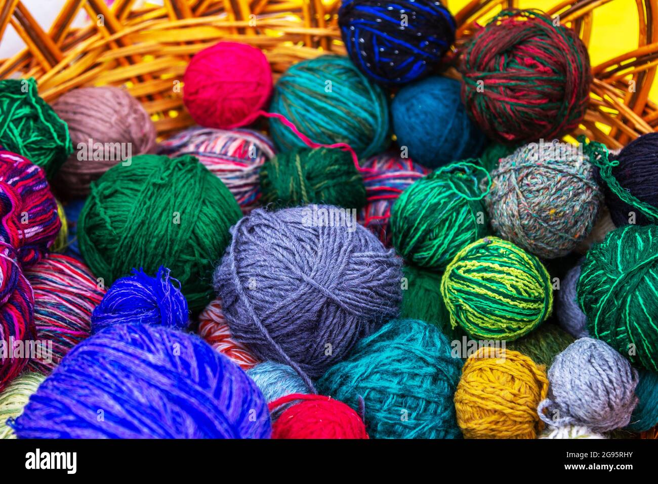 Palle colorate di filato da maglieria - filo di lana e cotone in un cestino di vimini. Foto Stock