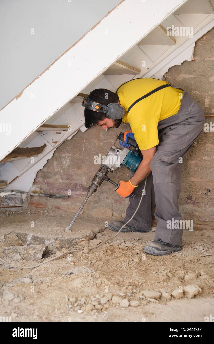Giovane cantiere caucasico che rompe il pavimento di una casa con un  martello pneumatico Foto stock - Alamy
