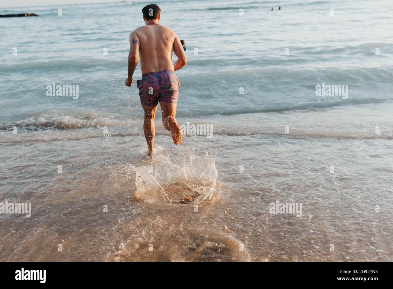 Gli adulti maschi corrono e si tuffano nell'oceano sulla spiaggia di Waikiki Foto Stock