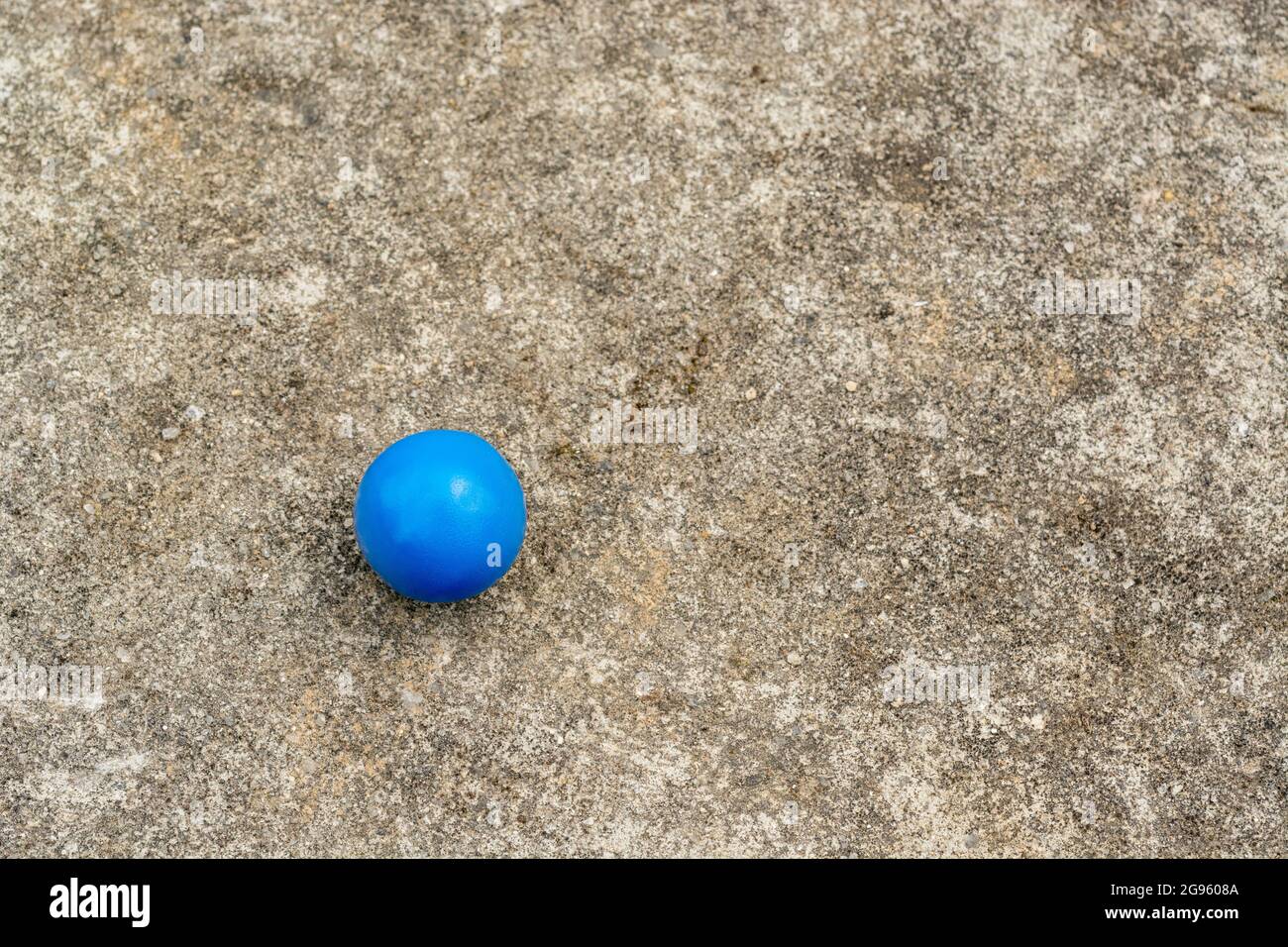 Sfera di plastica blu sulla superficie di cemento resistente alle intemperie + spazio per la copia. Per 'tutto da solo', isolamento, singolare, palla blu, palla in campo, astratta solitudine Foto Stock