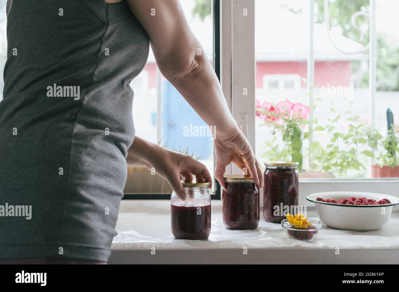 Donna che prende vasi di confettura di lamponi su tre Foto Stock