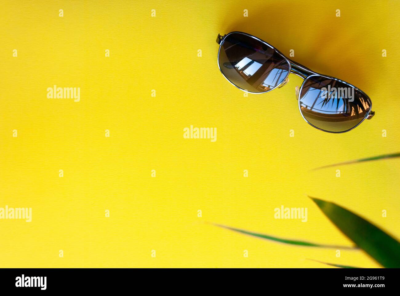 Occhiali da sole aviatori su sfondo giallo, vista superiore Foto Stock