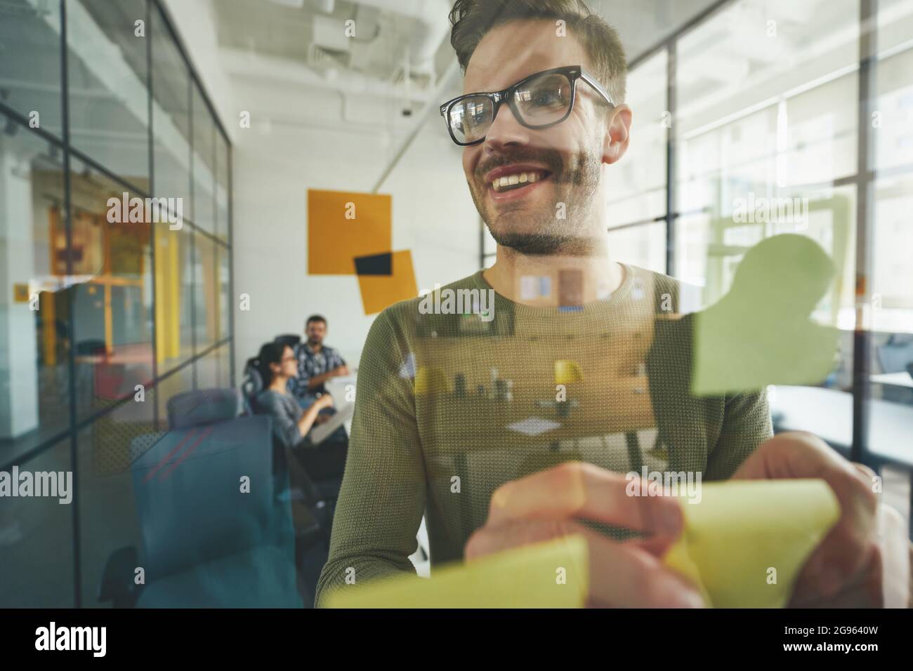 Leader energico del gruppo che mette pezzi di carta sulla parete Foto Stock