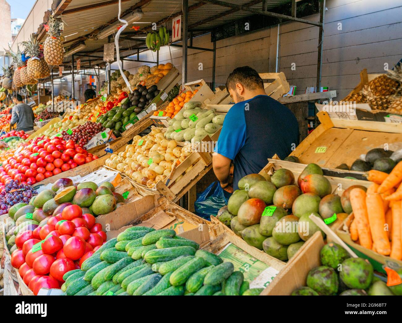 Vendor presso la mostra con frutta e verdura fresca al mercato all'aperto Sennoy, il più economico a San Pietroburgo, Russia Foto Stock