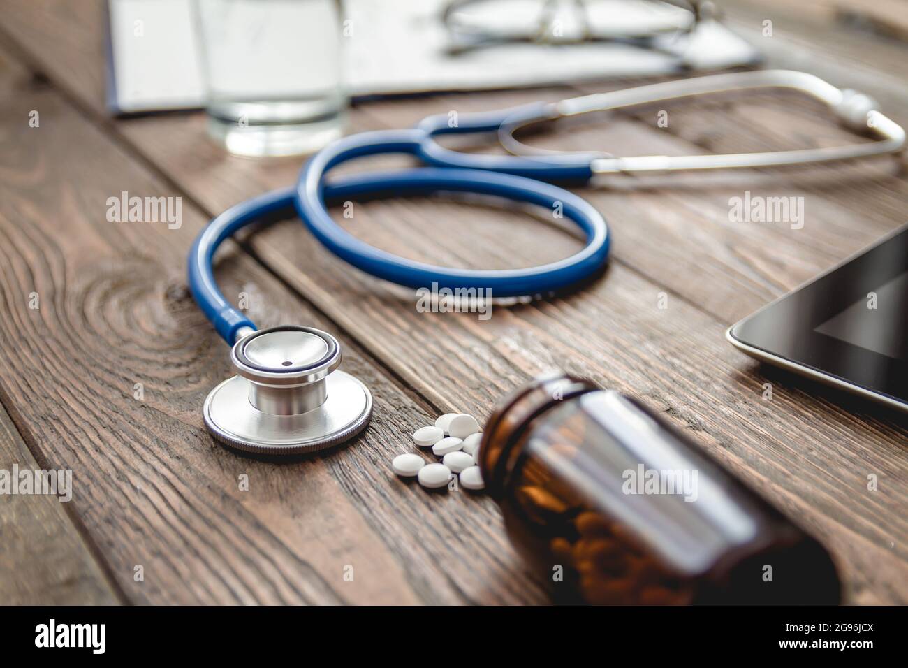 scheda medica del paziente primo piano, uno stetoscopio e pillole sulla scrivania del medico Foto Stock