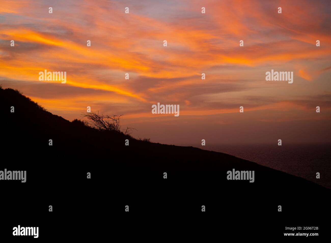 Il tramonto rossastro mostra un cielo con nuvole arancioni al Faro di Punta Gallina, la Guajira, Colombia Foto Stock