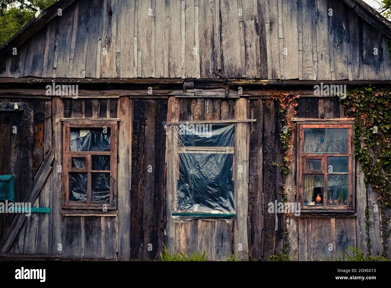 Facciata con finestre di una casa in legno molto vecchio dilapido Foto Stock