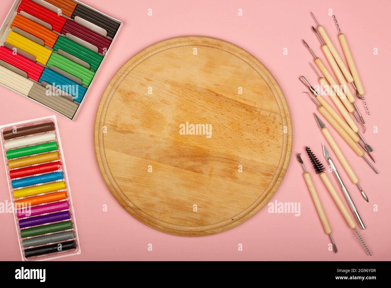 Kit di strumenti per la modellazione di plastiline su sfondo rosa.  Scrivania in legno in classe per lezioni con i bambini della scuola.  Strumenti di scultura per argilla polimerica Foto stock 