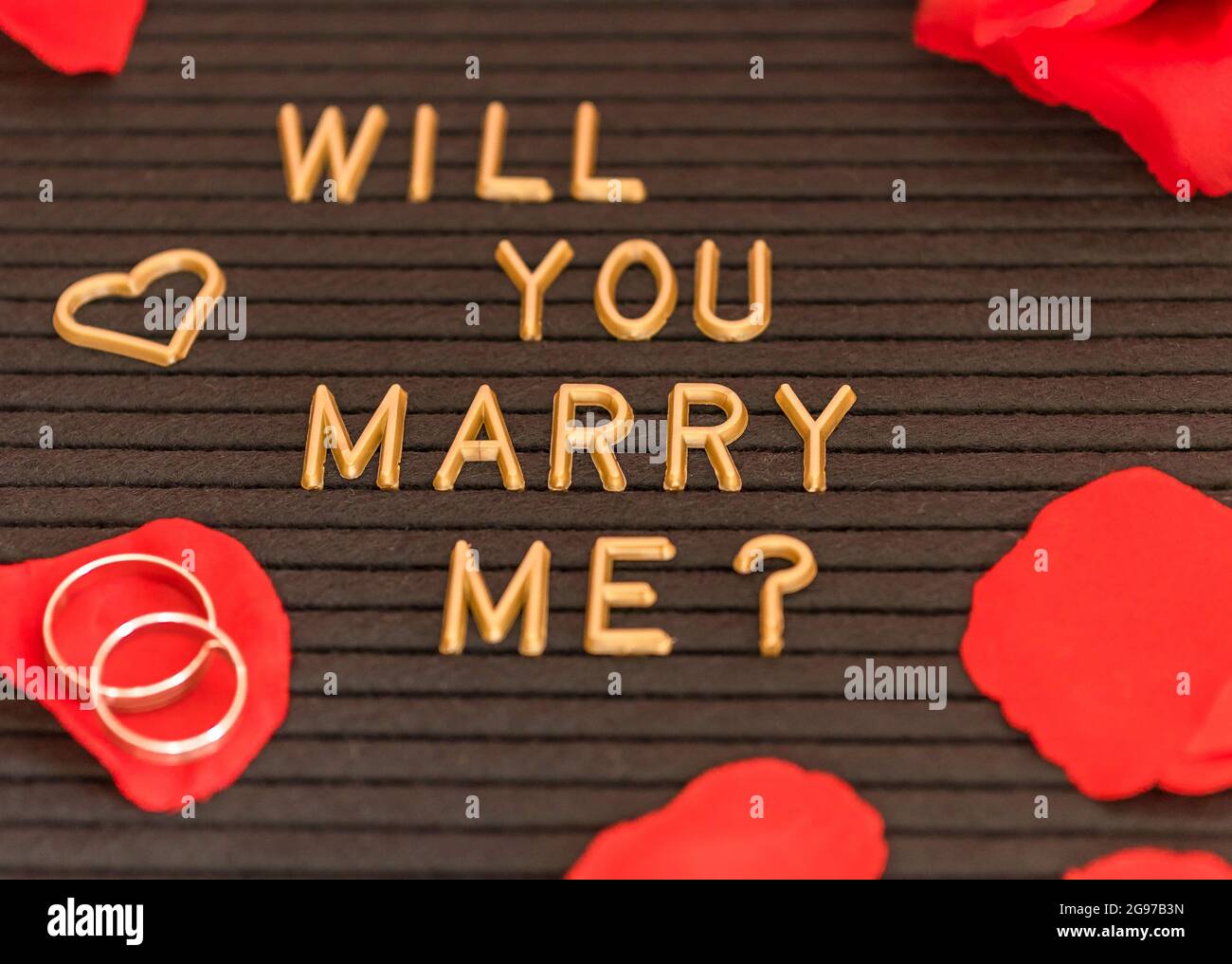 Un primo piano di un 'mi sposerai? testo scritto su una lavagna nera per una proposta Foto Stock
