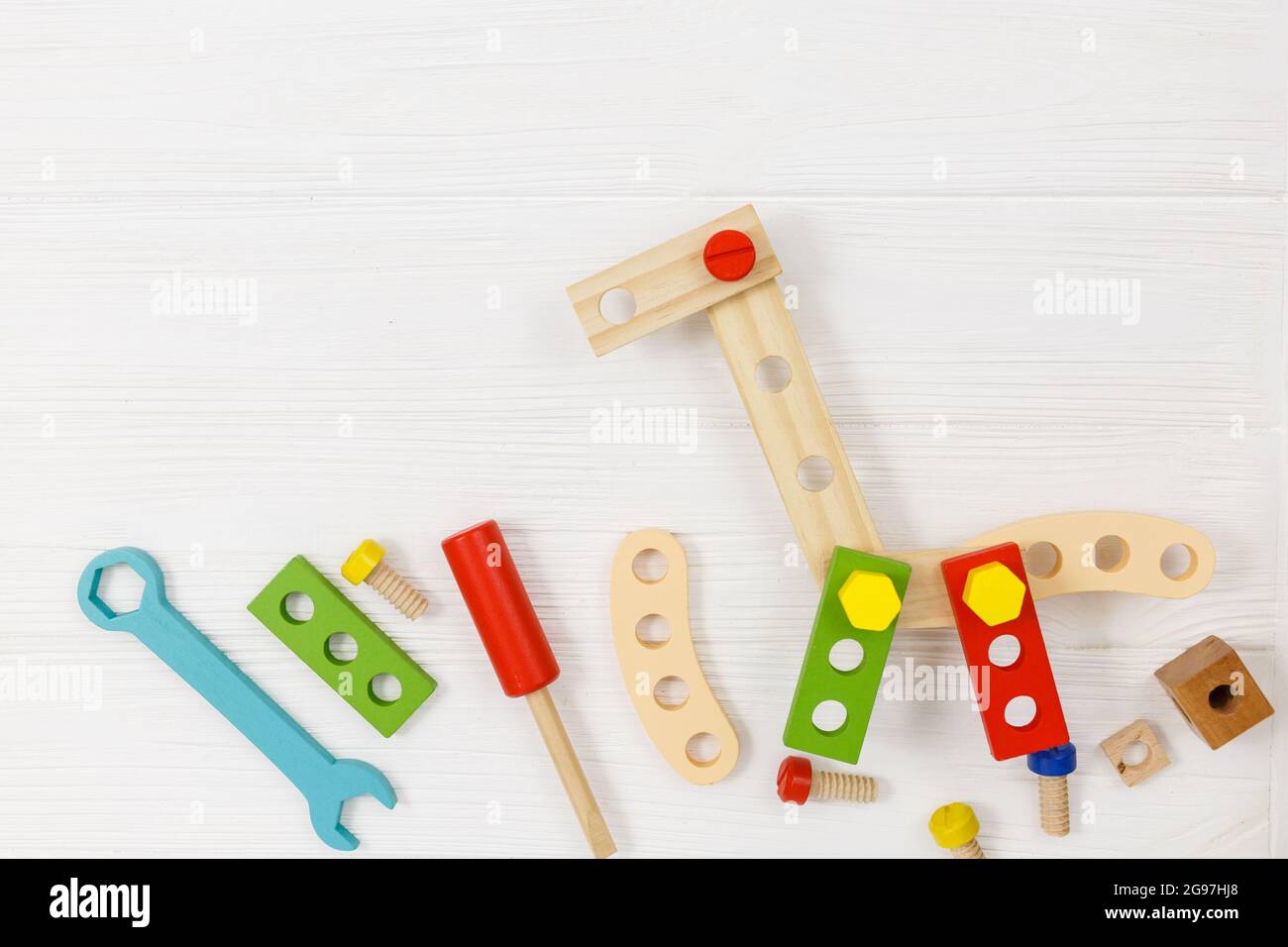 Una giraffa in legno colorato e kit da costruzione per bambini su legno. Set di attrezzi su tavolo di legno bianco. Giochi e strumenti per i bambini in età prescolare o in asilo Foto Stock