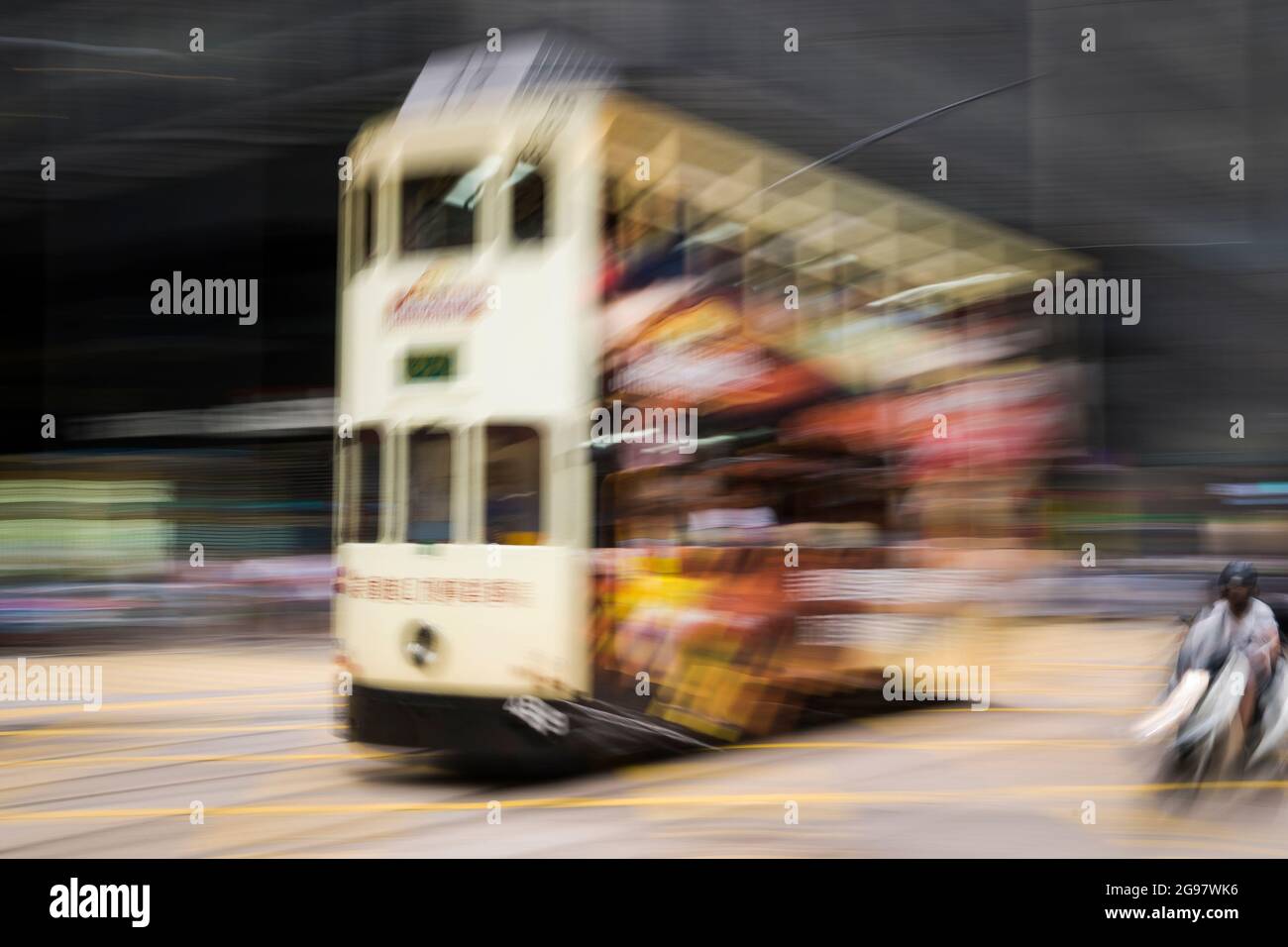 Un tram viaggia lungo Des Voeux Road, in centro, sull'isola di Hong Kong, in un'inquadratura con sfocatura del movimento selettiva dovuta al movimento della fotocamera Foto Stock