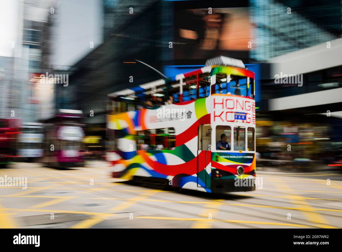 Un tram che mostra la livrea di Brand Hong Kong viaggia lungo Des Voeux Road, Central, Isola di Hong Kong, in una panoramica con sfocatura selettiva del movimento Foto Stock